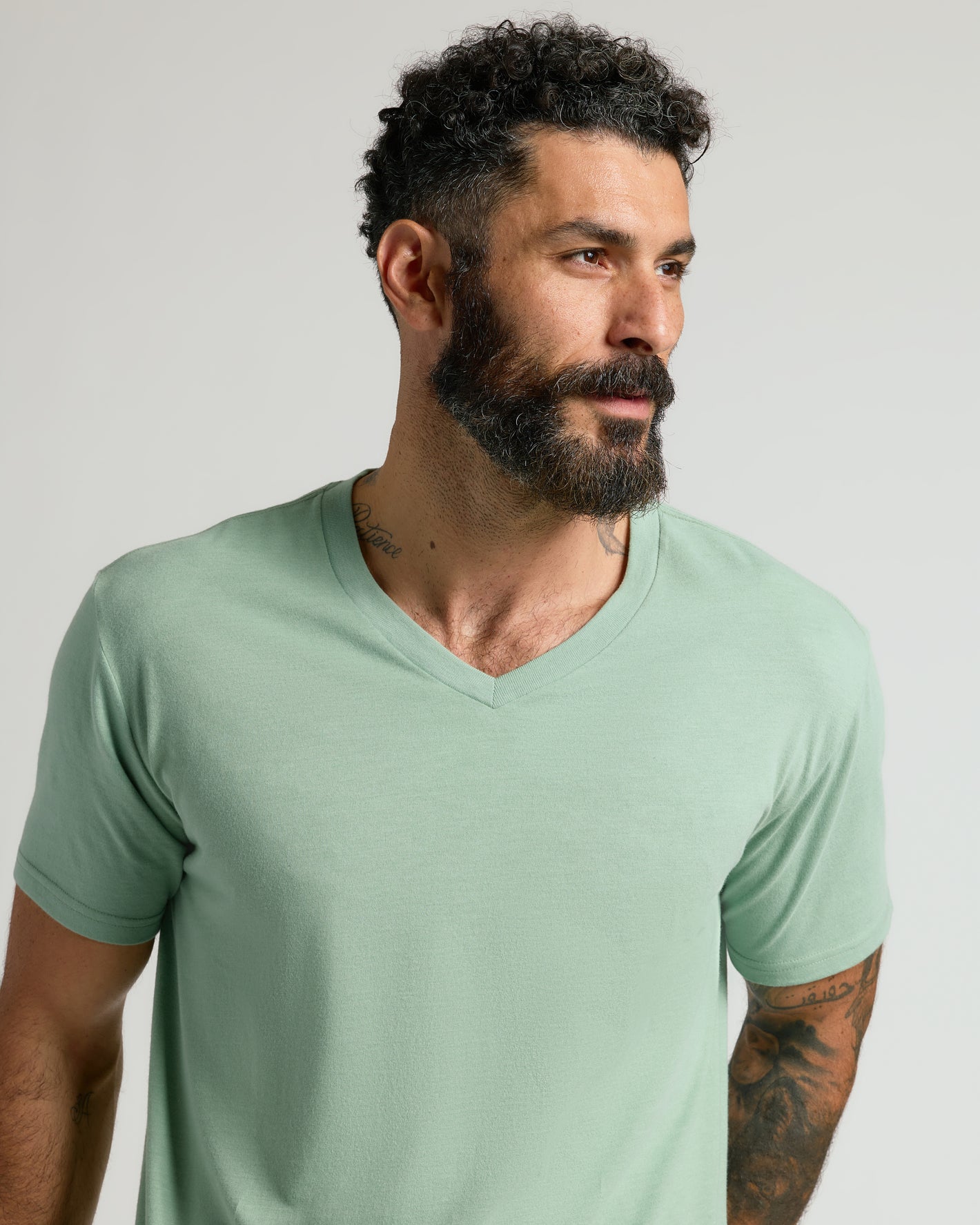 Man in Heather Slate Green Classic V-Neck T-shirt, showcasing tattoos.