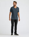 Man wearing a dark gray t-shirt and black pants on a white background