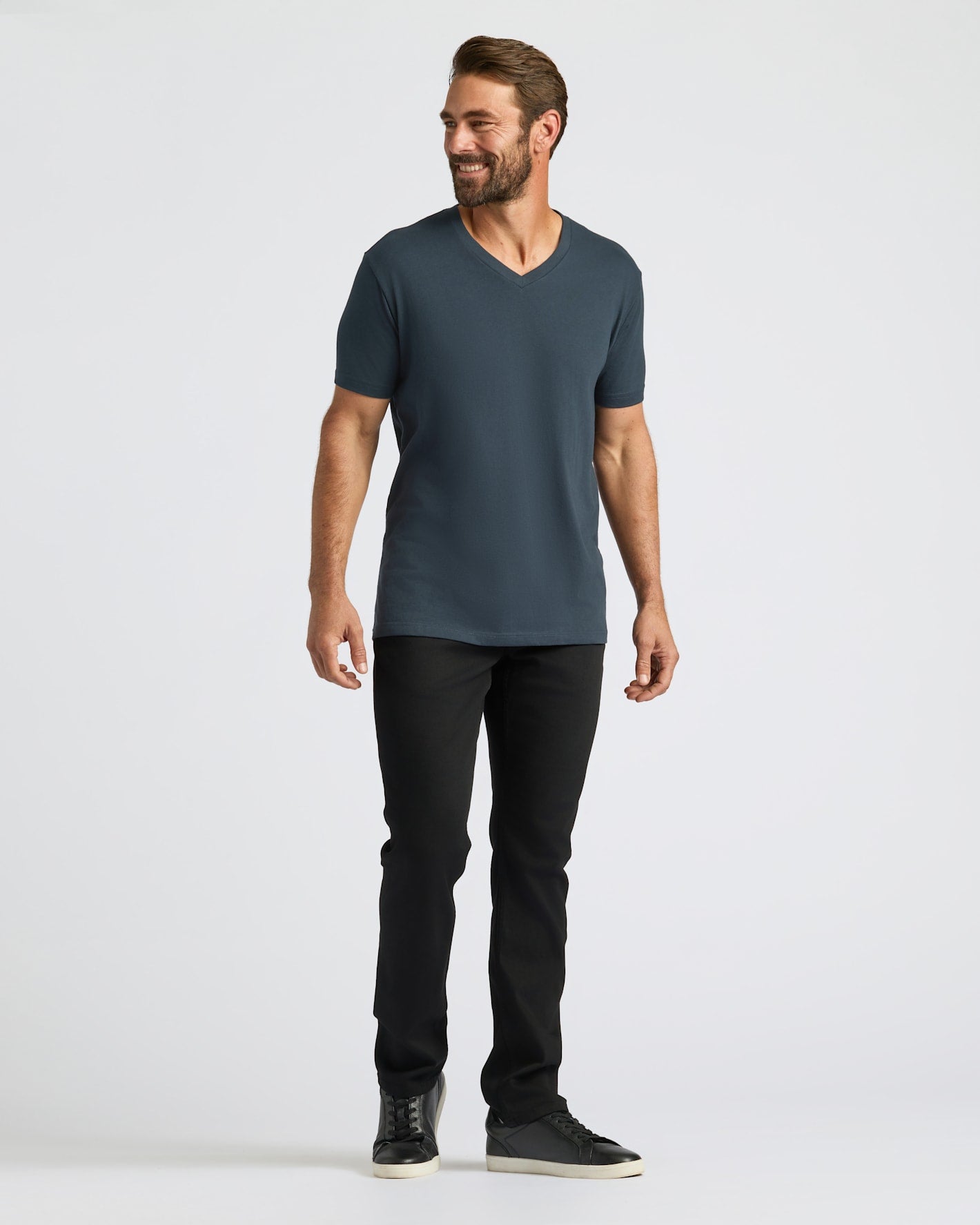 Man wearing a dark gray t-shirt and black pants on a white background