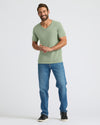 Man wearing a green t-shirt and blue jeans on a white background