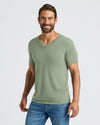 Man wearing a green t-shirt and blue jeans on a light gray background