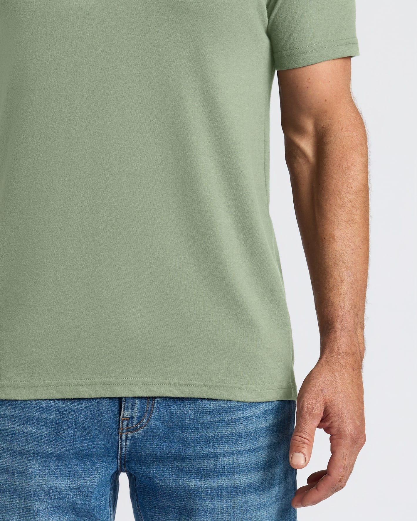 Person wearing a green t-shirt and blue jeans on a light gray background