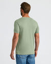 Man wearing a green t-shirt and blue jeans on a white background