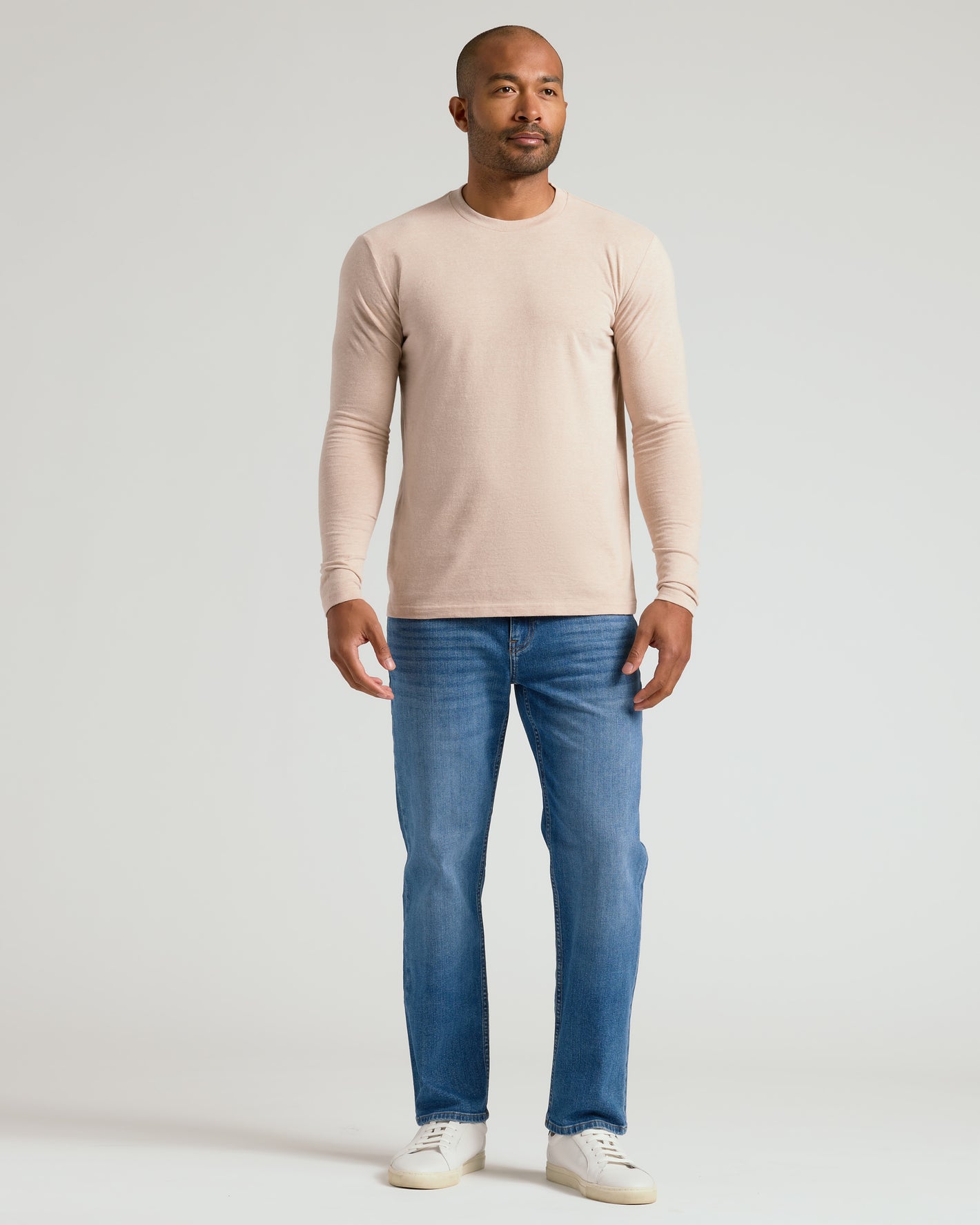 Man wearing Heather Camel Classic Long Sleeve Crew Neck, jeans, sneakers.