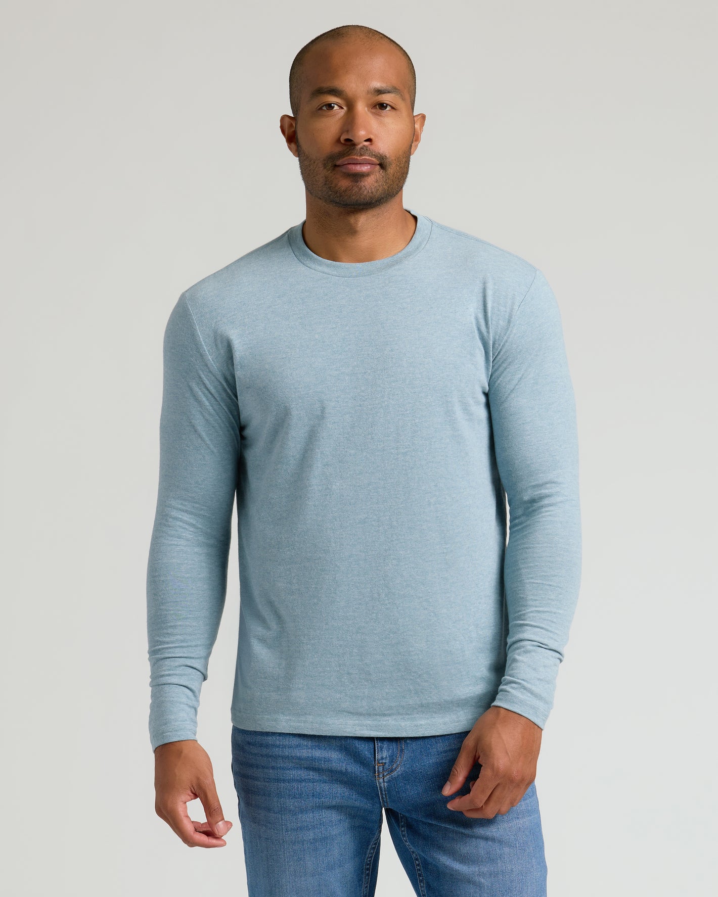 Man wearing Heather Sapphire Classic Long Sleeve Crew Neck and jeans.
