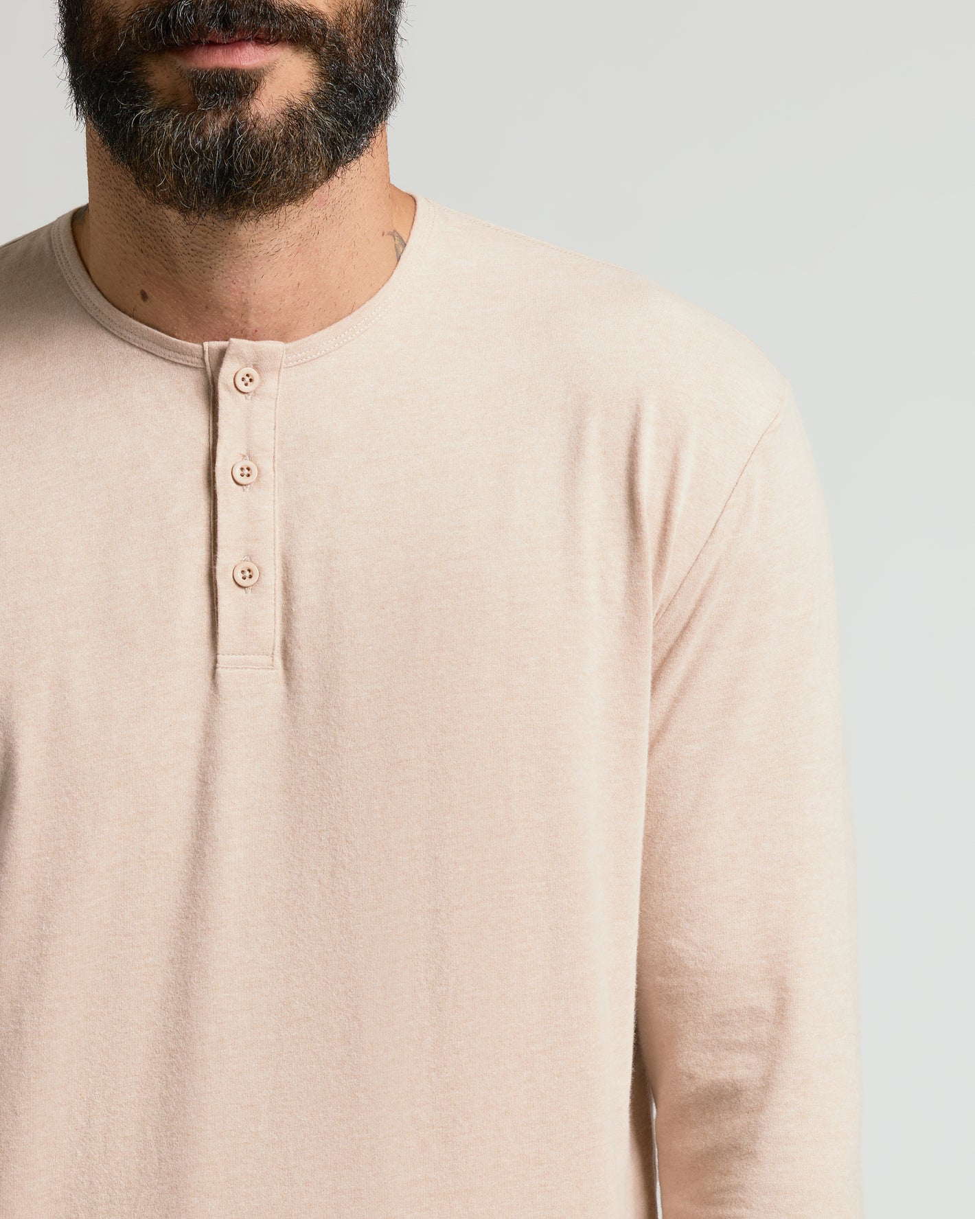 Man wearing Heather Camel Classic Long Sleeve Henley with buttoned neckline.
