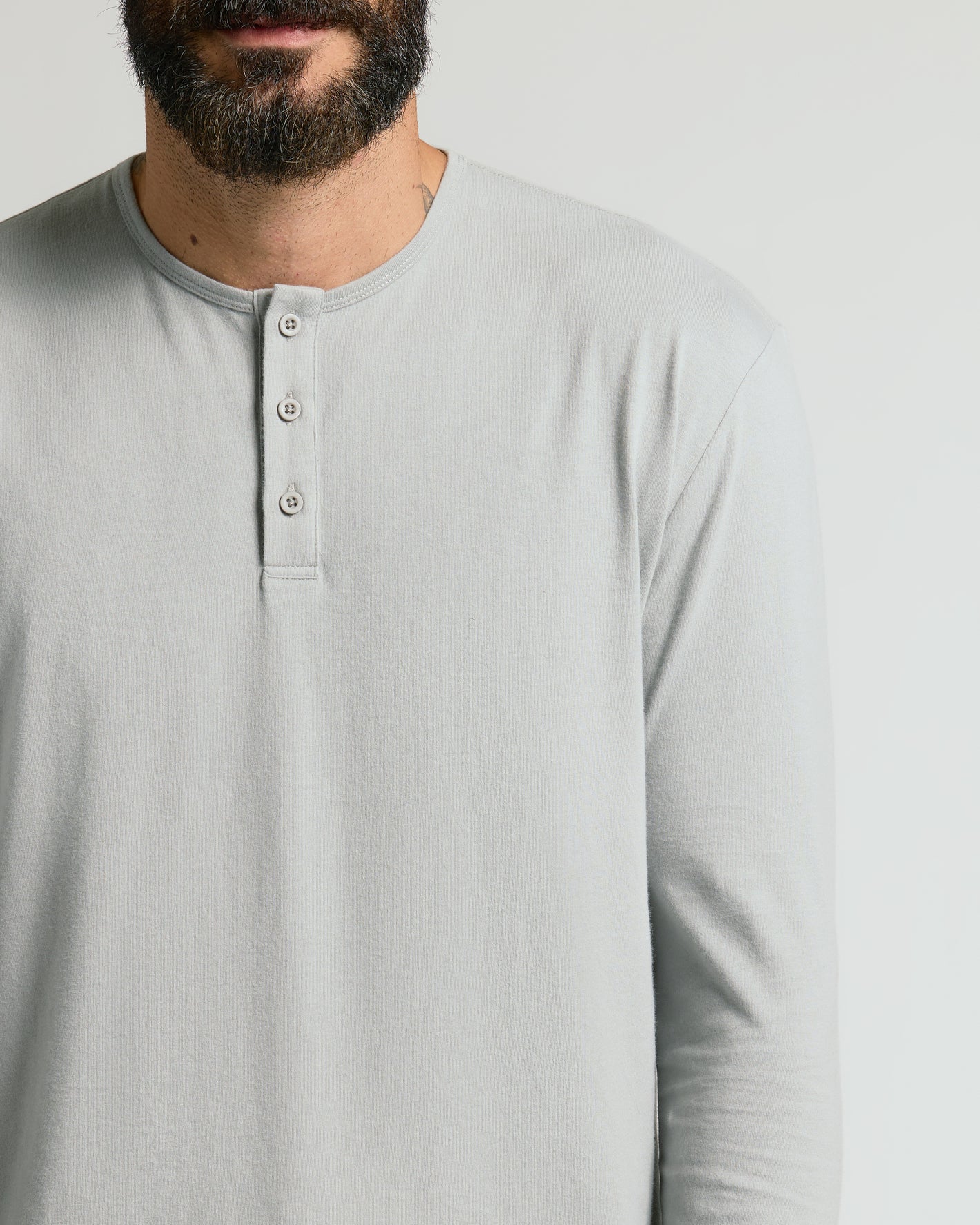 Steel Classic Long Sleeve Henley on man, showcasing buttons and light-gray fabric.