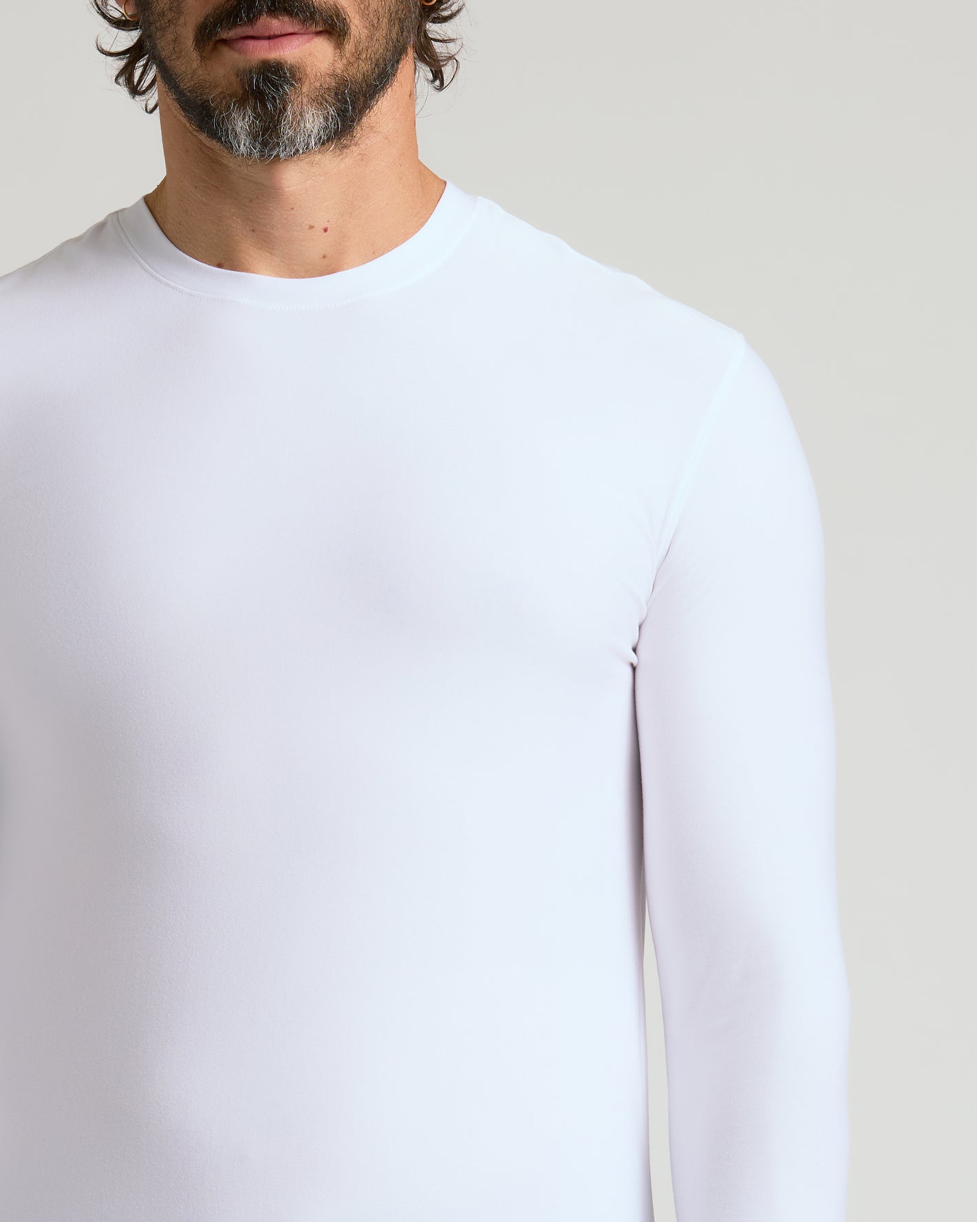 Man wearing Active Long Sleeve Crew, white snug-fit, highlighting comfort and style.