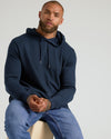 Man wearing Heather Gray & Navy Waffle Hoodie, seated, showing hoodie features.