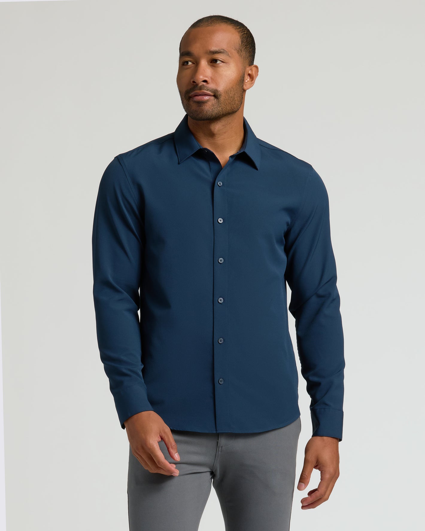 Man models Staple Long Sleeve Performance Dress Shirt, deep teal-blue, tucked in.