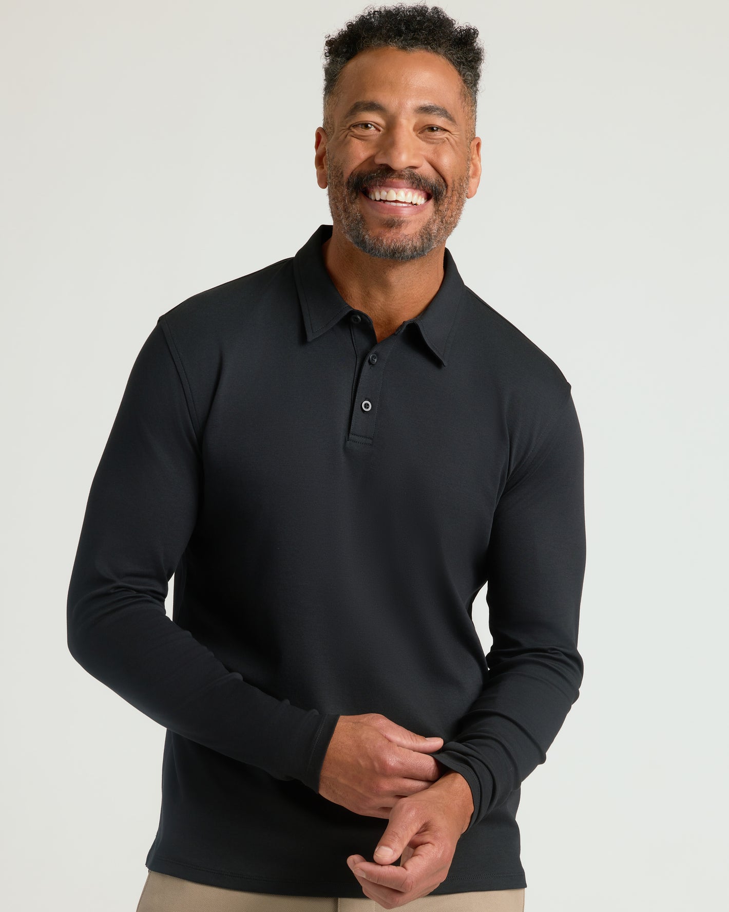 Man wearing Black Long Sleeve Premium Pima Polo, adjusting sleeve.