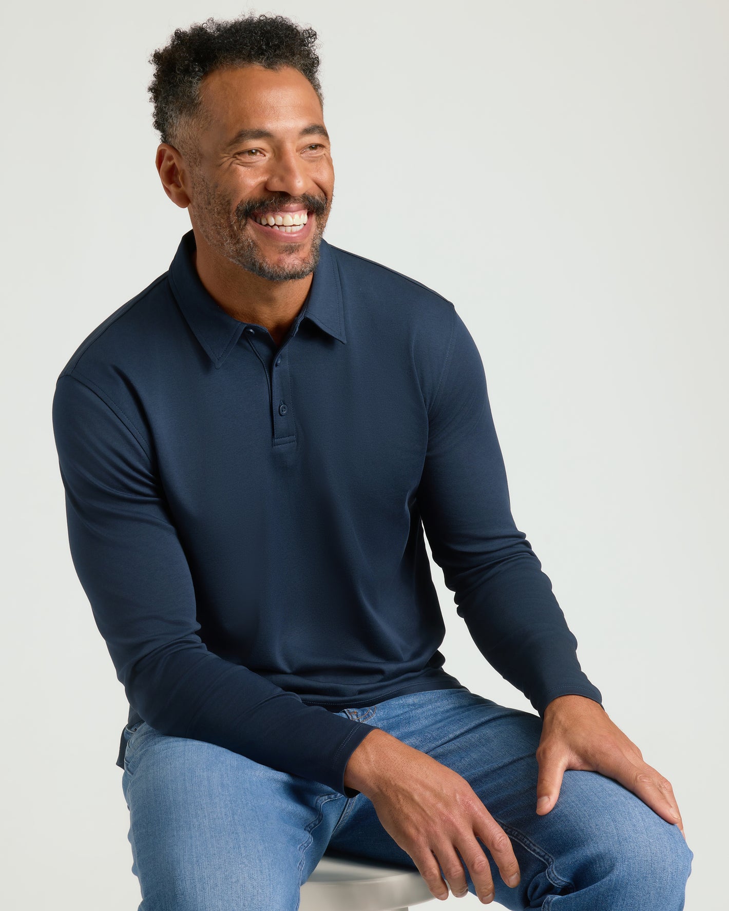 Man wearing All Navy Long Sleeve Premium Pima Polo, smiling comfortably.