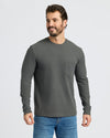 Man wearing Carbon Heavyweight Long Sleeve Pocket Crew with jeans, smiling.