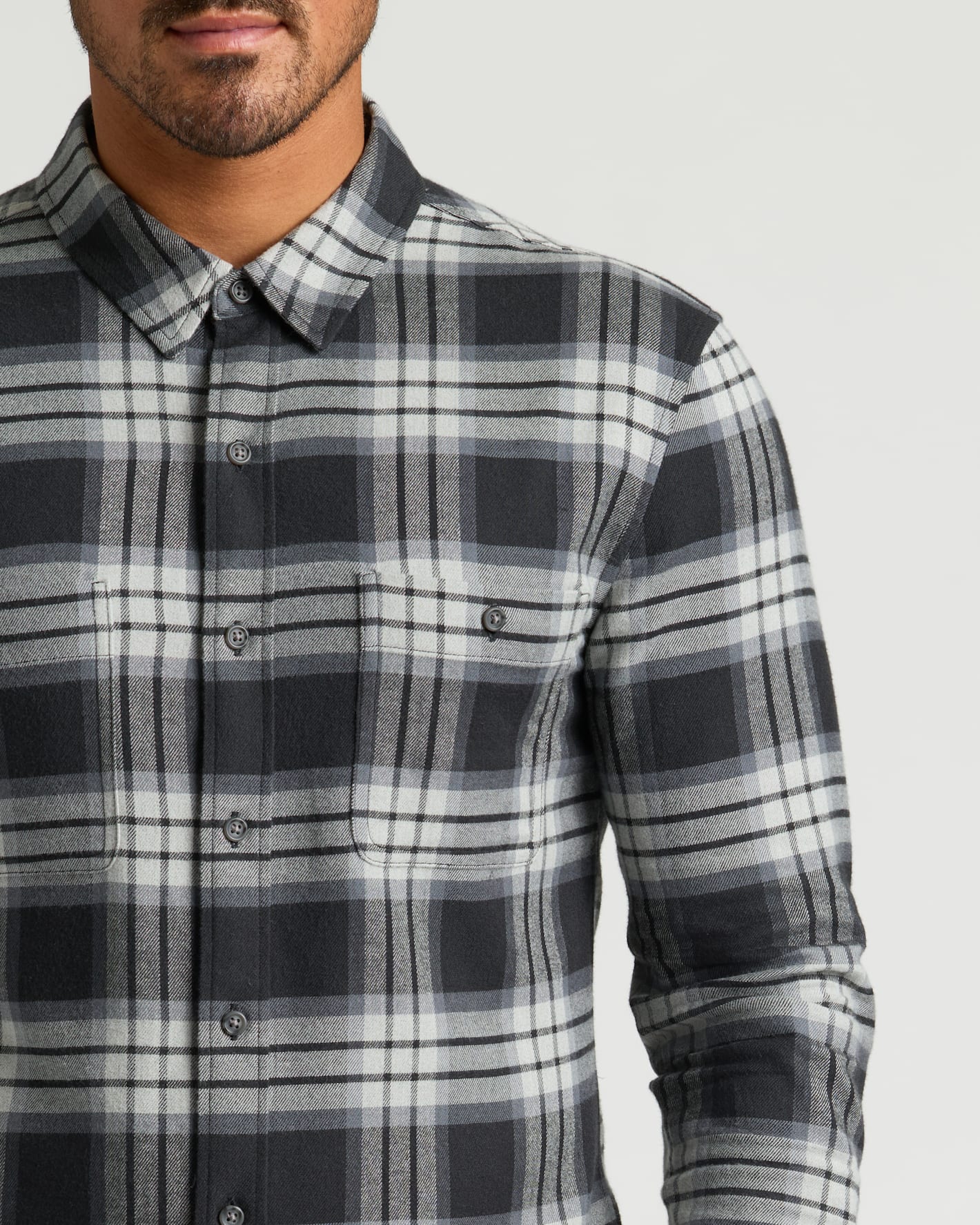 Man wearing Onyx Plaid Long Sleeve Flannel Shirt, buttoned, with chest pocket.