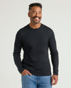 Man in All Black Premium Pima Long Sleeve Crew, smiling confidently.
