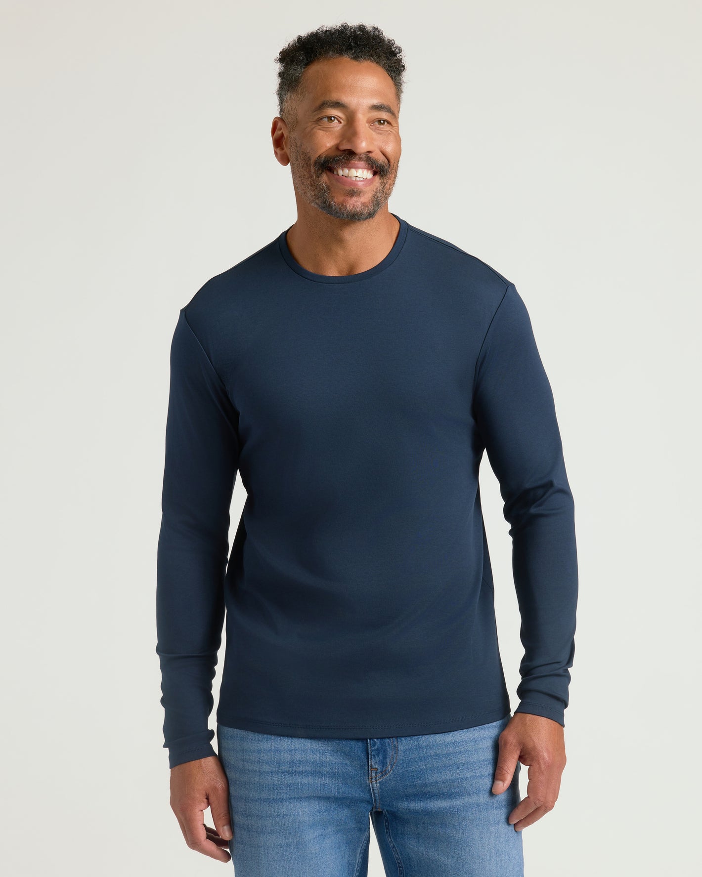 Man in Navy Premium Pima Long Sleeve Crew, light-wash jeans.
