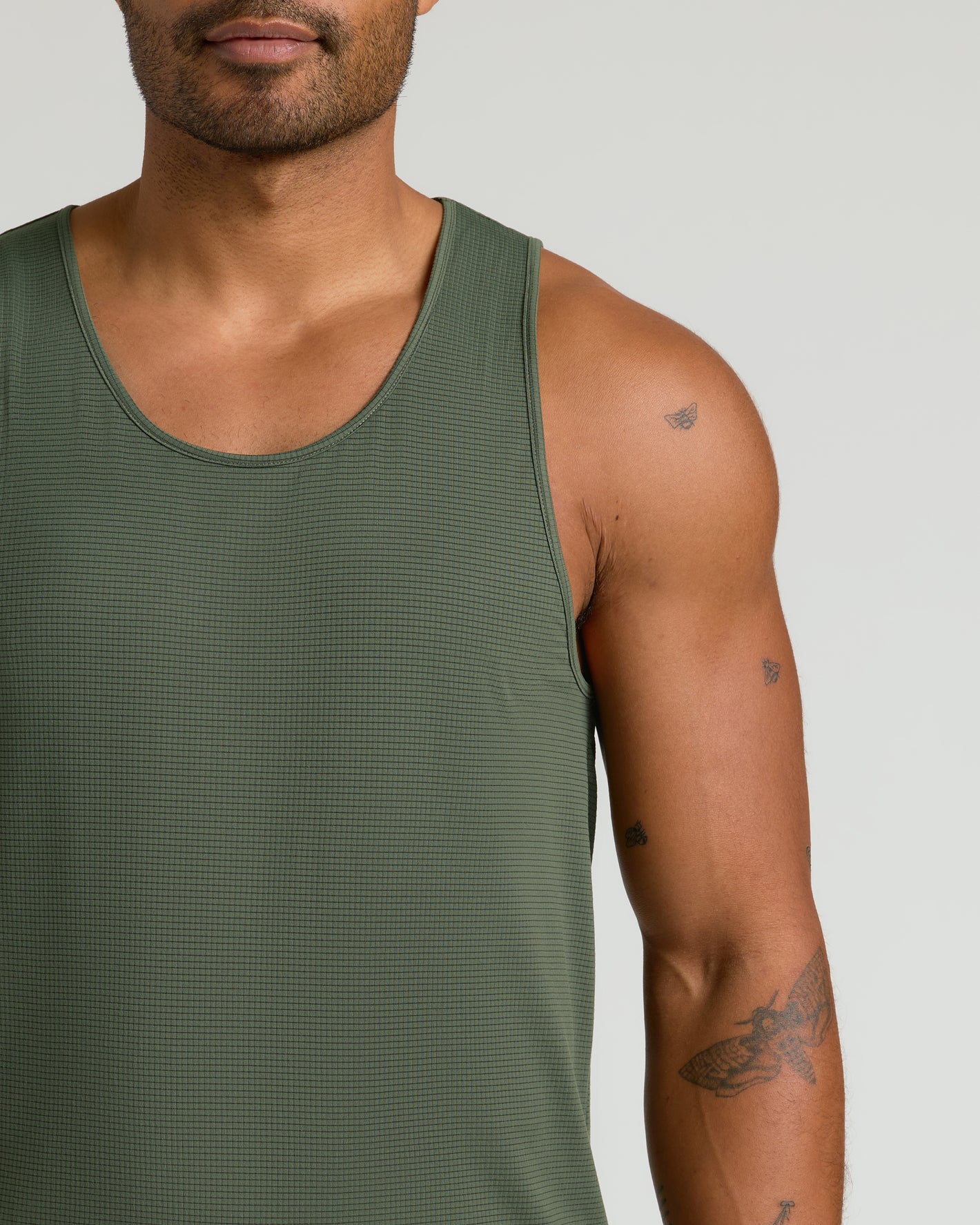 Man wearing Kelp Sleeveless Active Mesh Tank with insect tattoos visible.