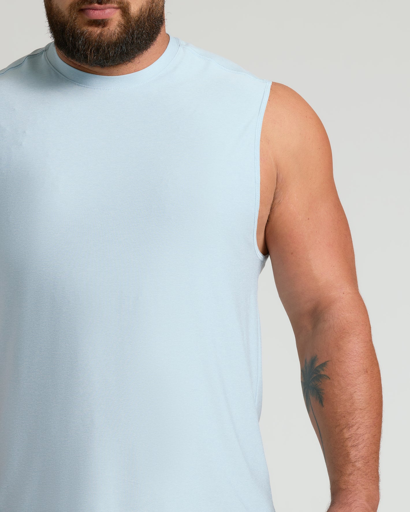 Man in Arctic Sleeveless Active Muscle Tee, showcasing a palm-tree tattoo.