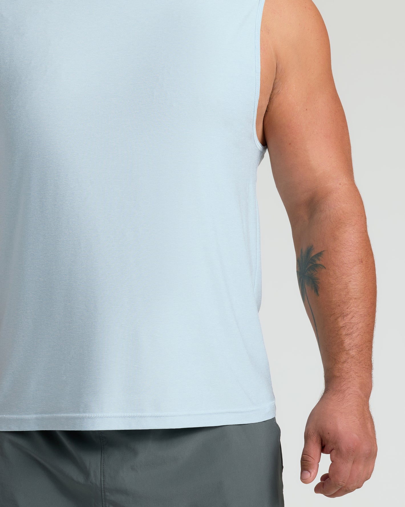 Arctic Sleeveless Active Muscle Tee worn with dark shorts, palm-tree tattoo visible.