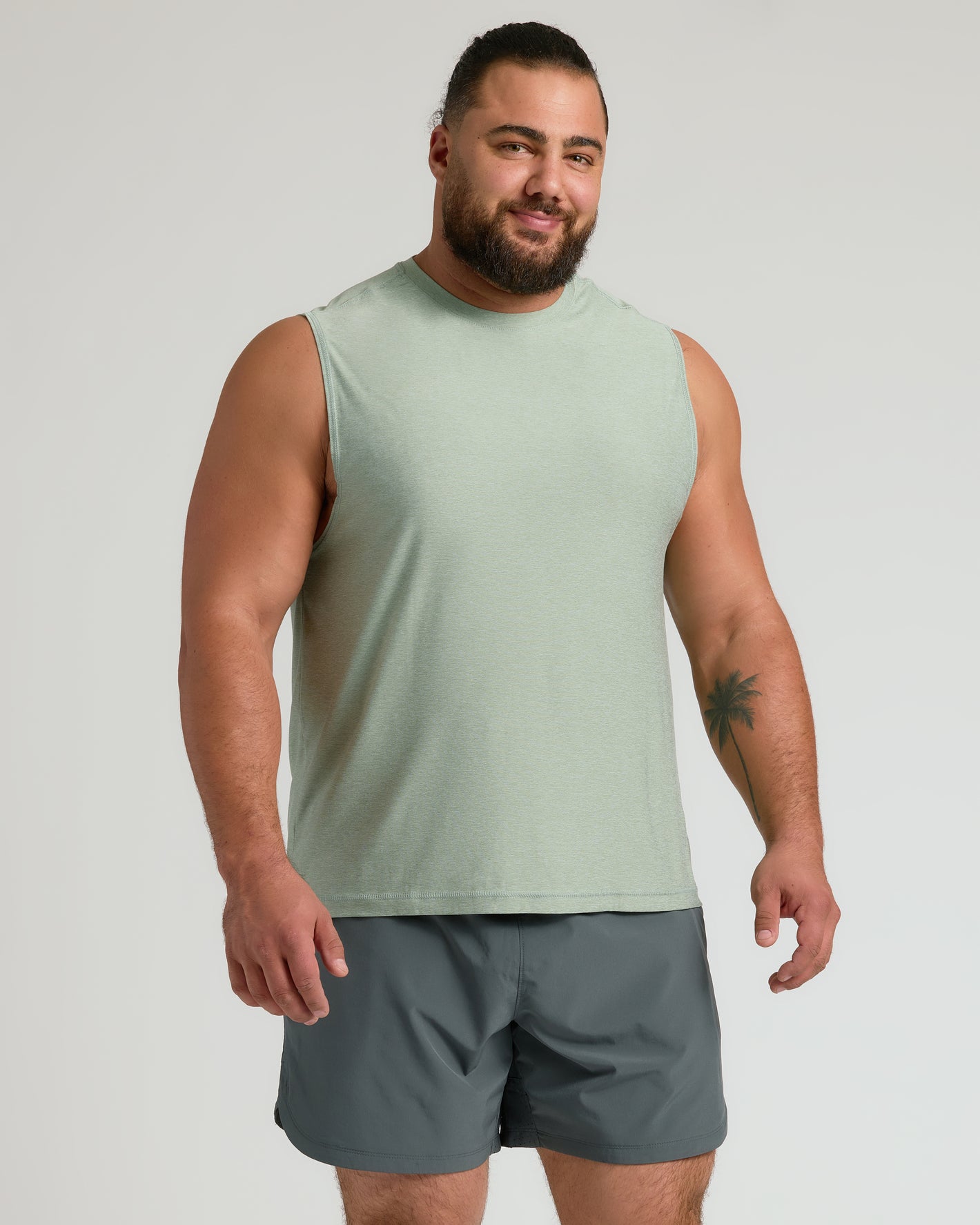 Man in Limited Spring Sleeveless Active Muscle Tee, sage green, dark gray shorts.