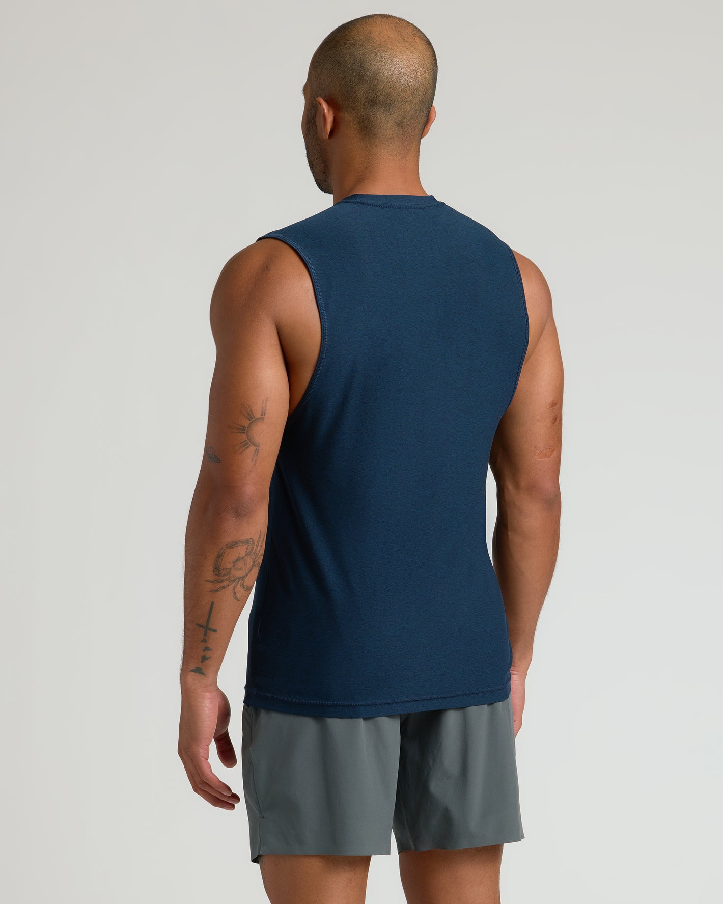 Man in Dark Heather Navy Sleeveless Active Muscle Tee, tattoos visible.