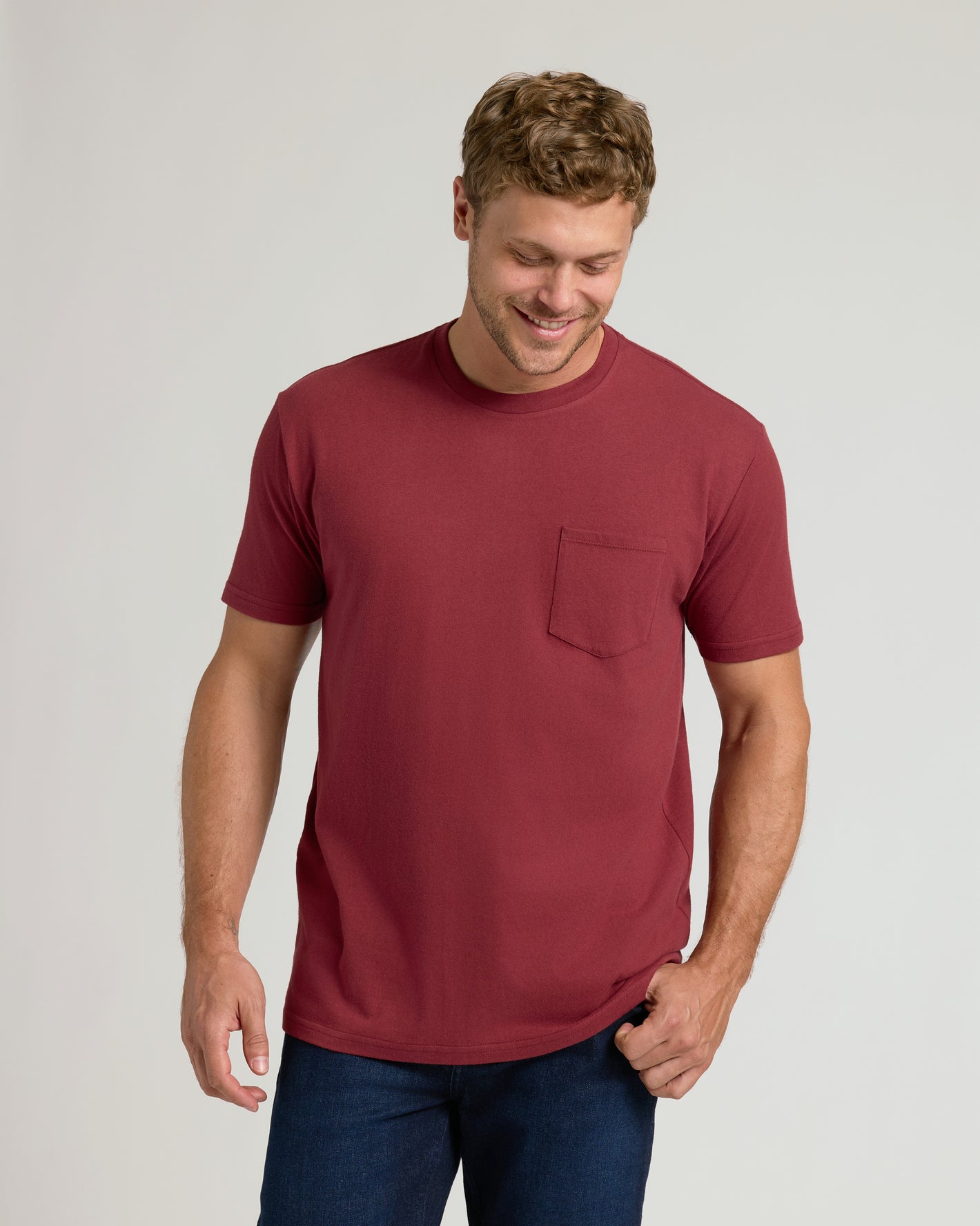 Young man in Claret Pocket Crew Tee and dark jeans, smiling.