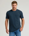 Model in Navy Pocket Crew Tee and jeans, adjusting shirt hem.
