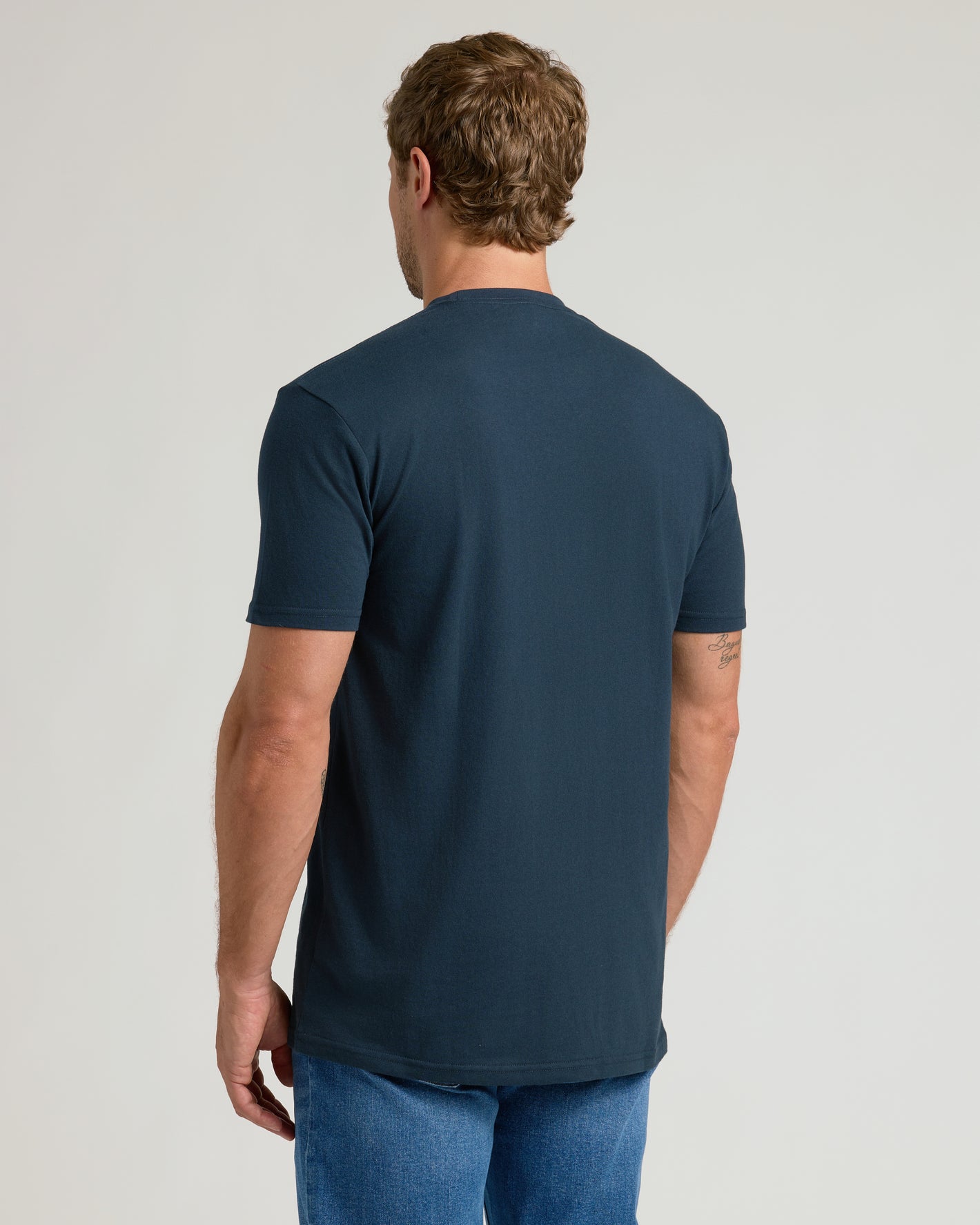 Back view of model in Navy Pocket Crew Tee and medium-wash jeans.