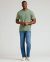Man wearing a green t-shirt and blue jeans on a white background