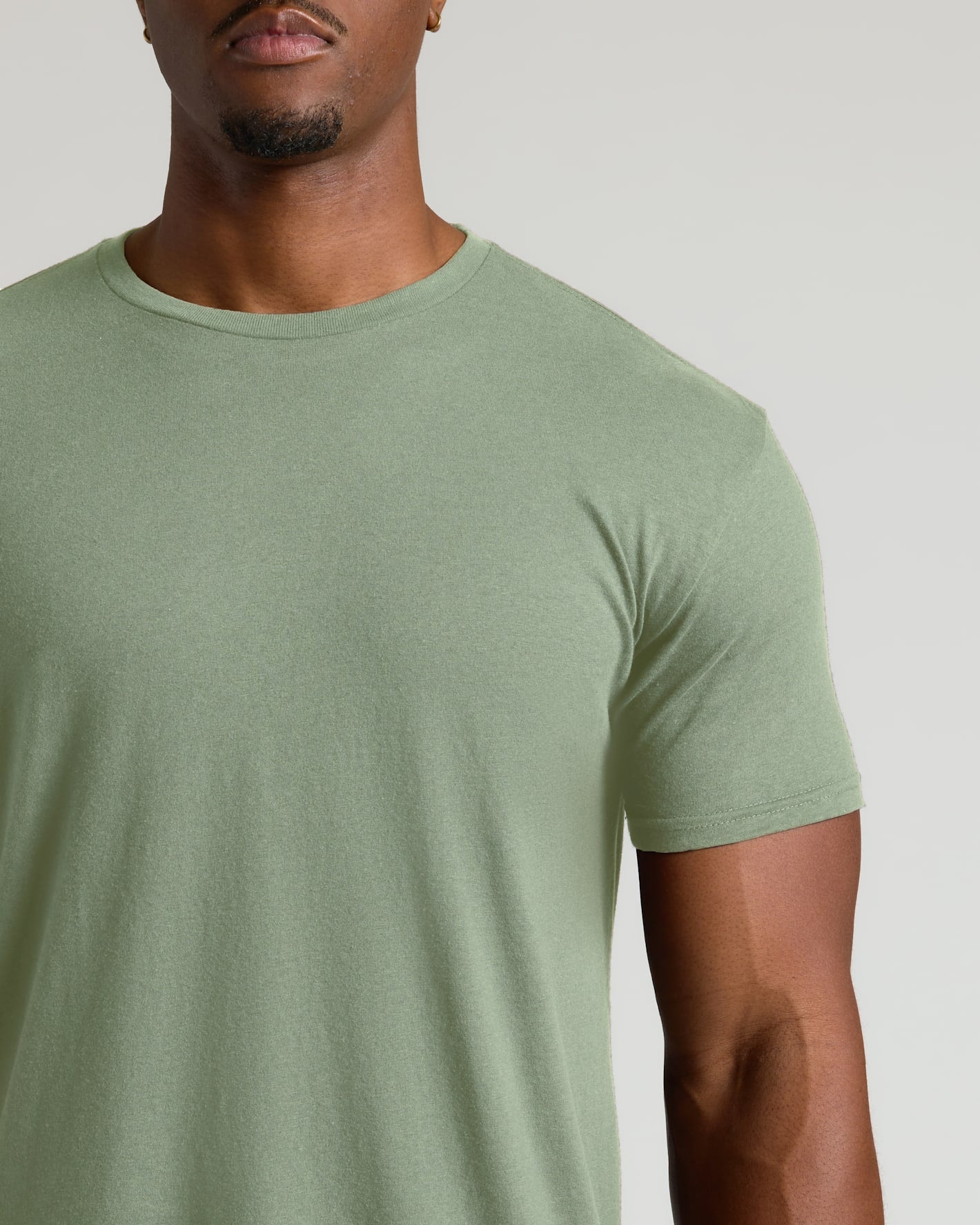 Man wearing a plain green t-shirt against a neutral background
