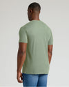 Man wearing a green t-shirt and blue jeans on a light gray background