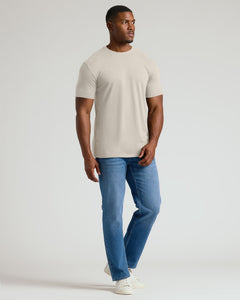True ClassicMan wearing a beige t-shirt and blue jeans on a white background