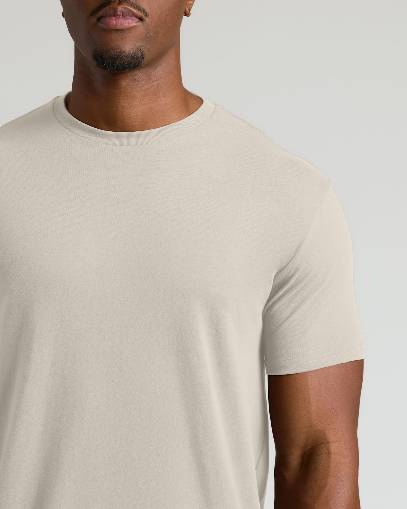 Man wearing a plain beige t-shirt against a light gray background