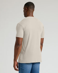 True ClassicMan wearing a beige t-shirt and blue jeans on a light gray background