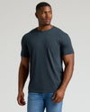 Man wearing a dark gray t-shirt and blue jeans on a light gray background