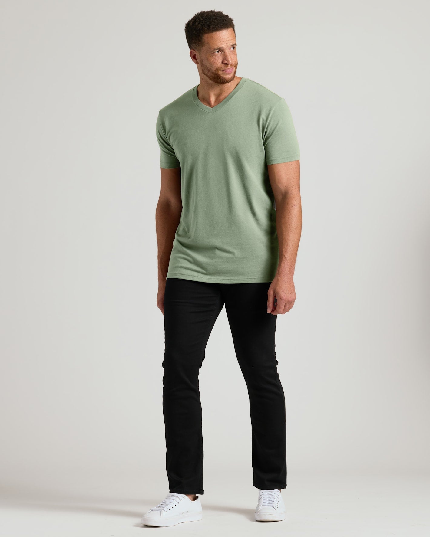 Man wearing a green t-shirt and black pants on a white background