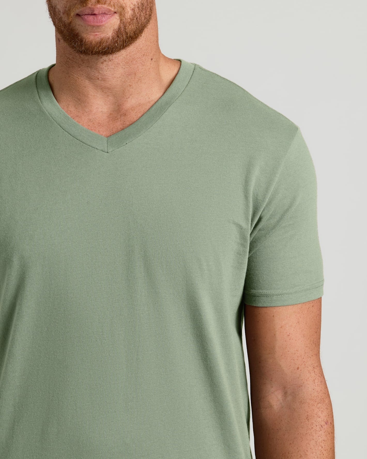 Man wearing a green V-neck t-shirt on a light gray background