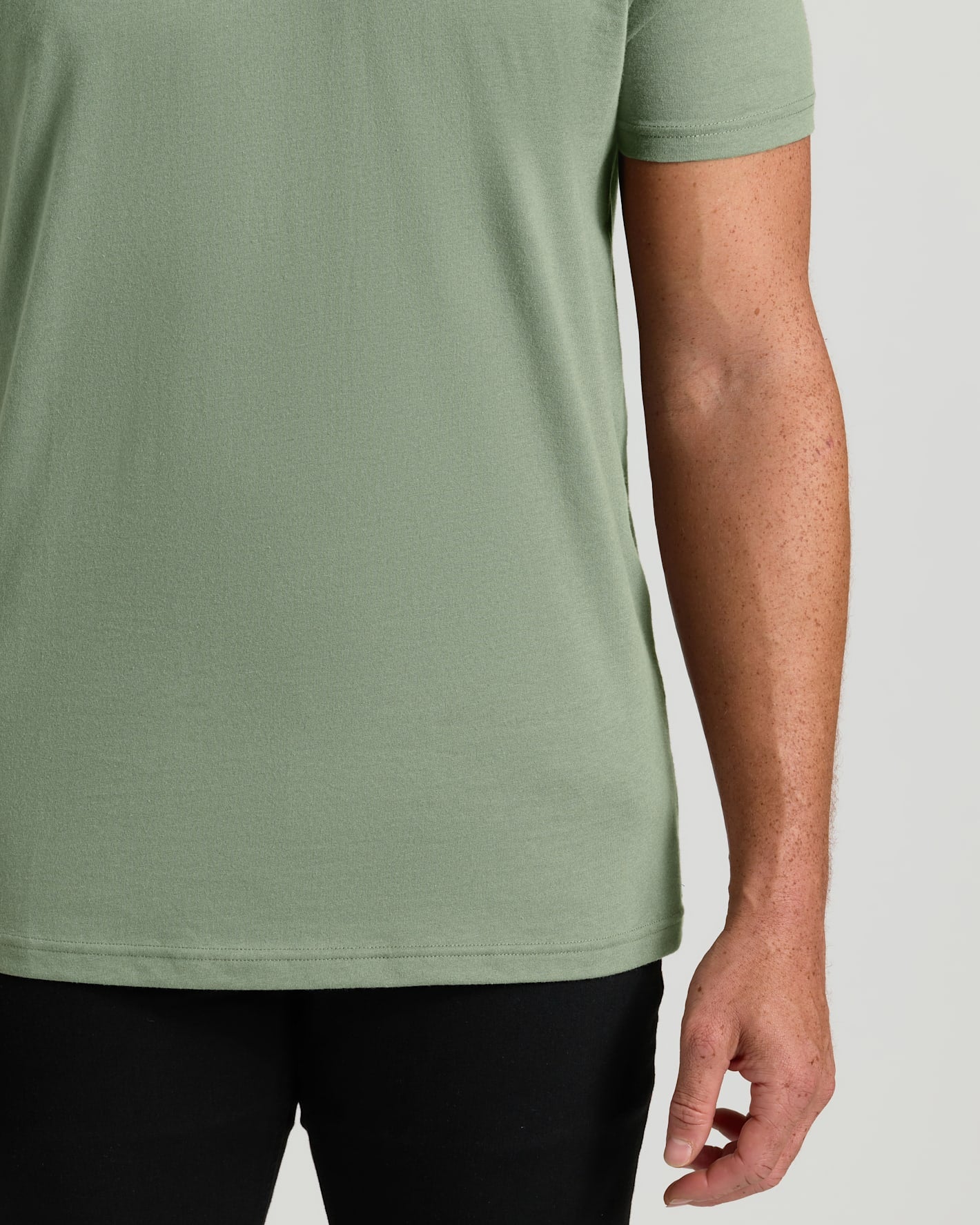 Person wearing a green t-shirt on a plain background