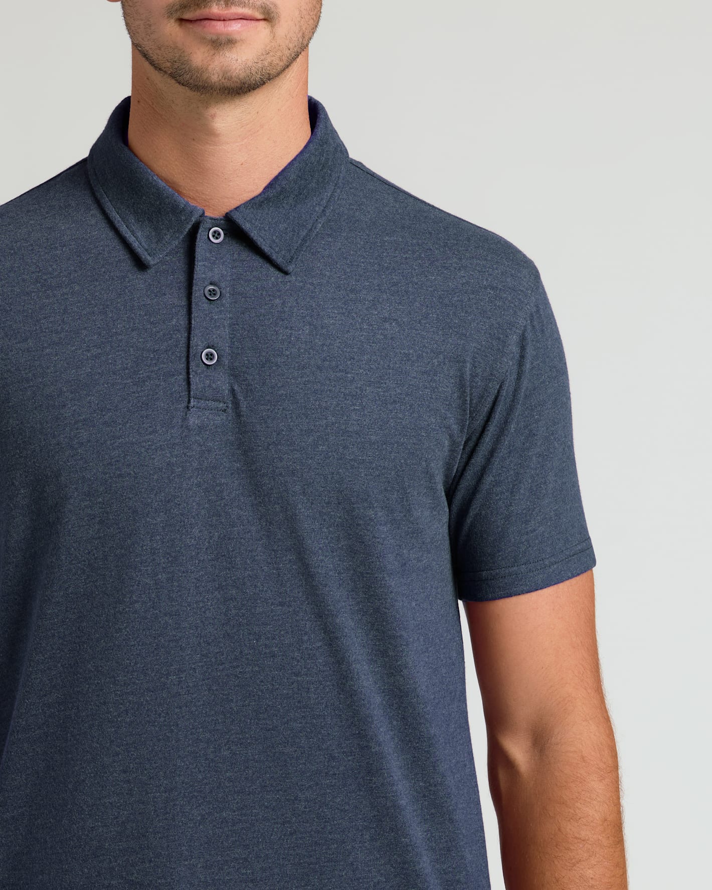 Man wearing a dark blue polo shirt on a light gray background