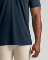 Close-up of a person wearing a dark navy short-sleeve athletic t-shirt and light beige compression leggings against a light gray studio background.