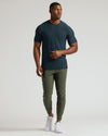 Man wearing a dark green t-shirt and olive green pants on a white background