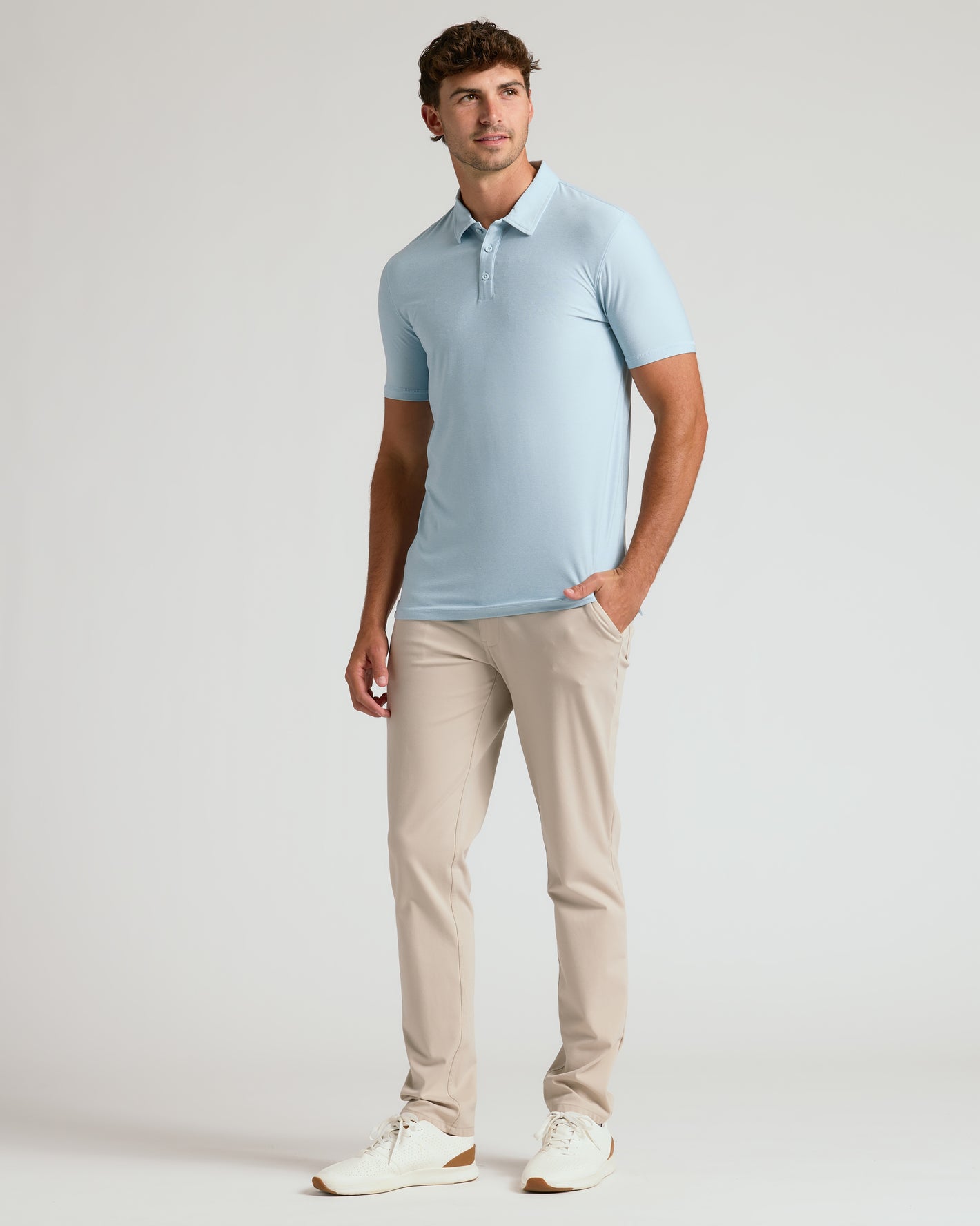 Man wearing Arctic Short Sleeve Tall Active Polo, beige pants, white sneakers.