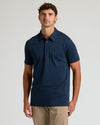 Navy Tall Pima Polo on man in light background.