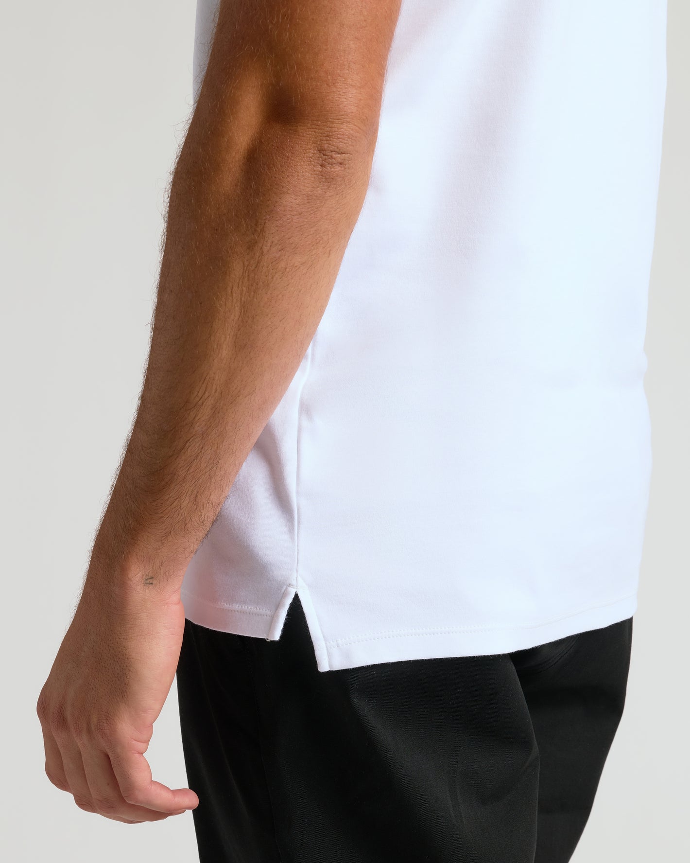 White Tall Premium Pima Polo with side-hem slit detail, worn with black trousers.
