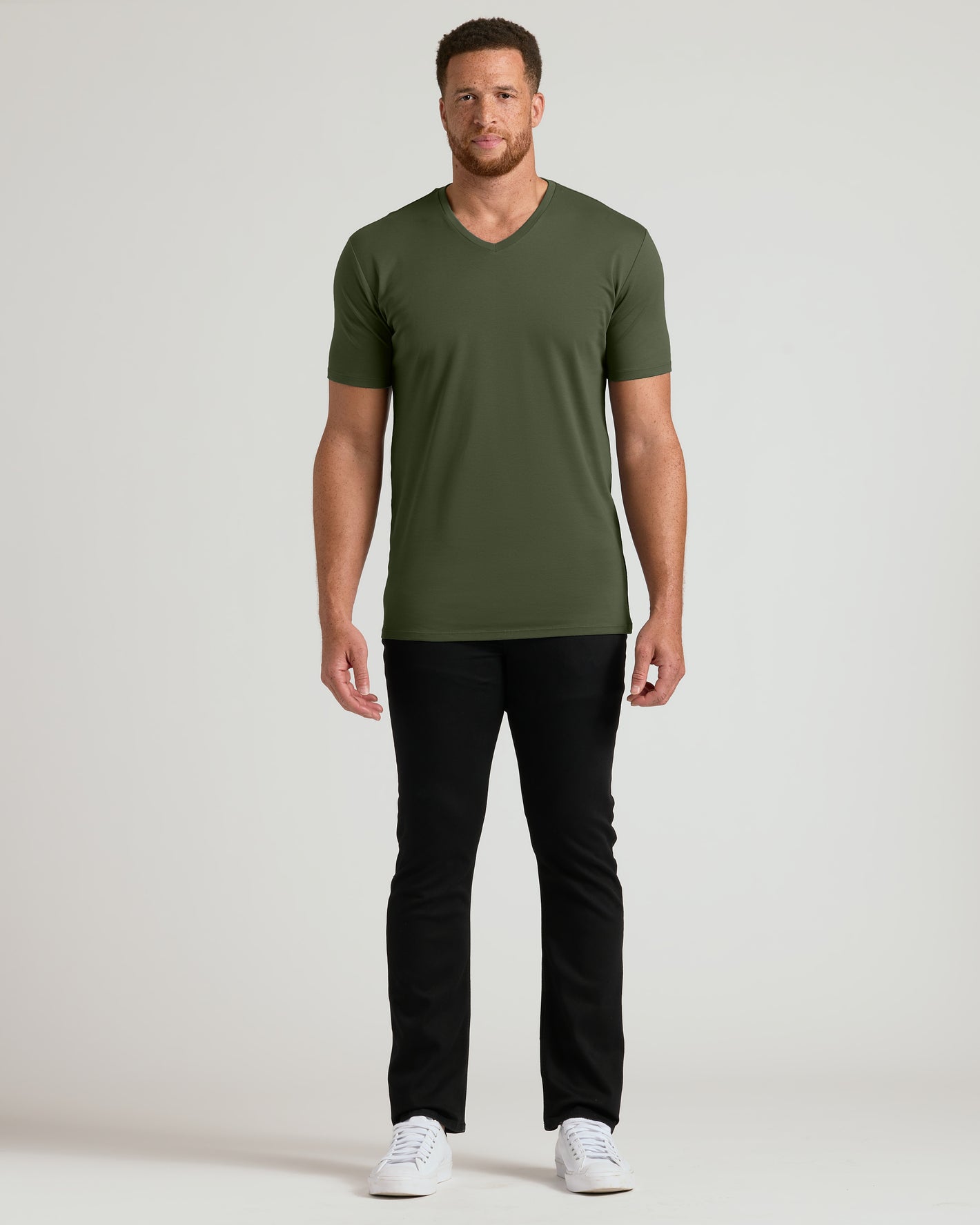 Man wearing Grove Tall Premium Pima V-Neck, black pants, white sneakers.
