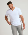 Man in White Tall Premium Pima V-Neck T-shirt, smiling, adjusting hem.