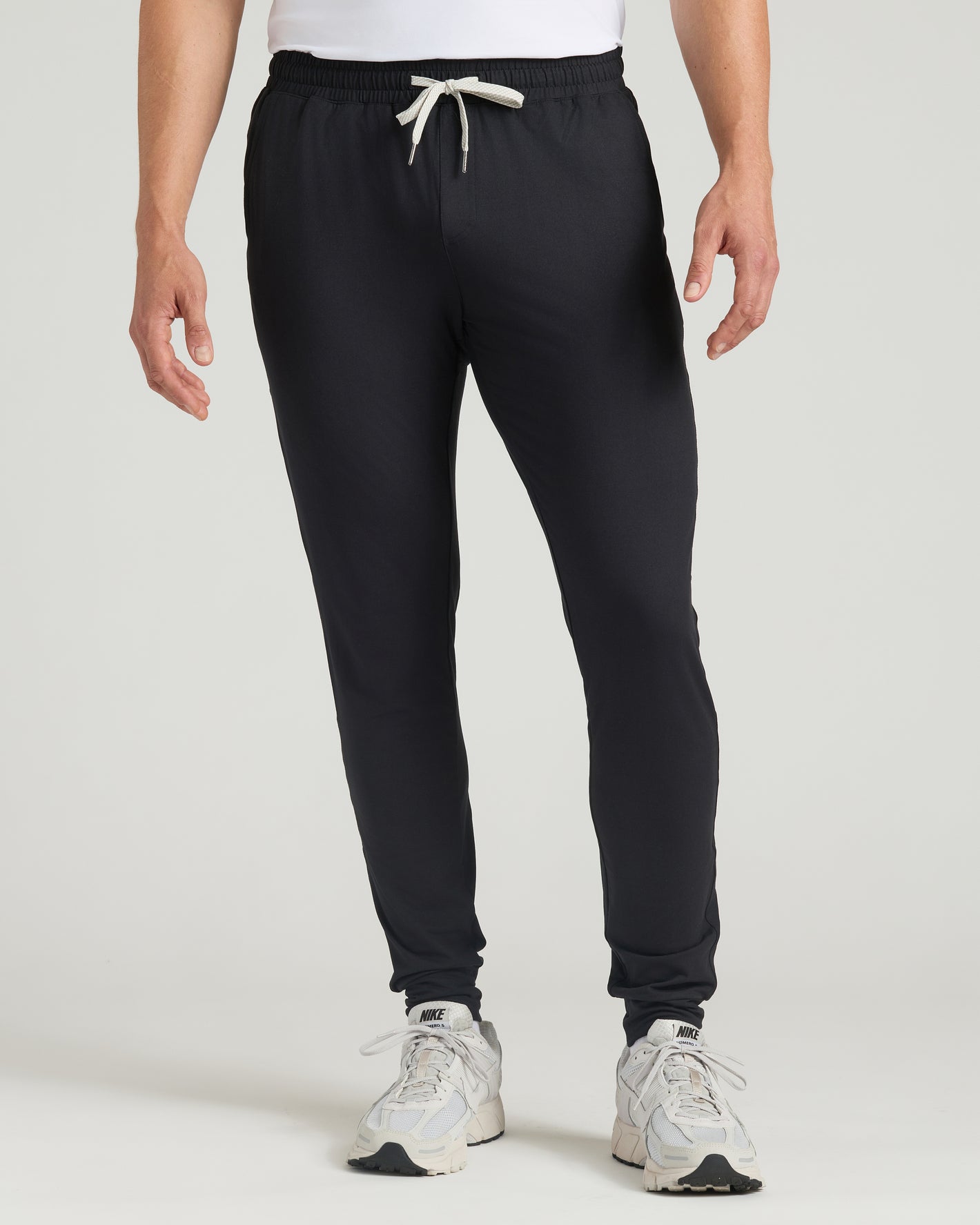 Black Tall Active Joggers on person with Nike shoes, studio background.