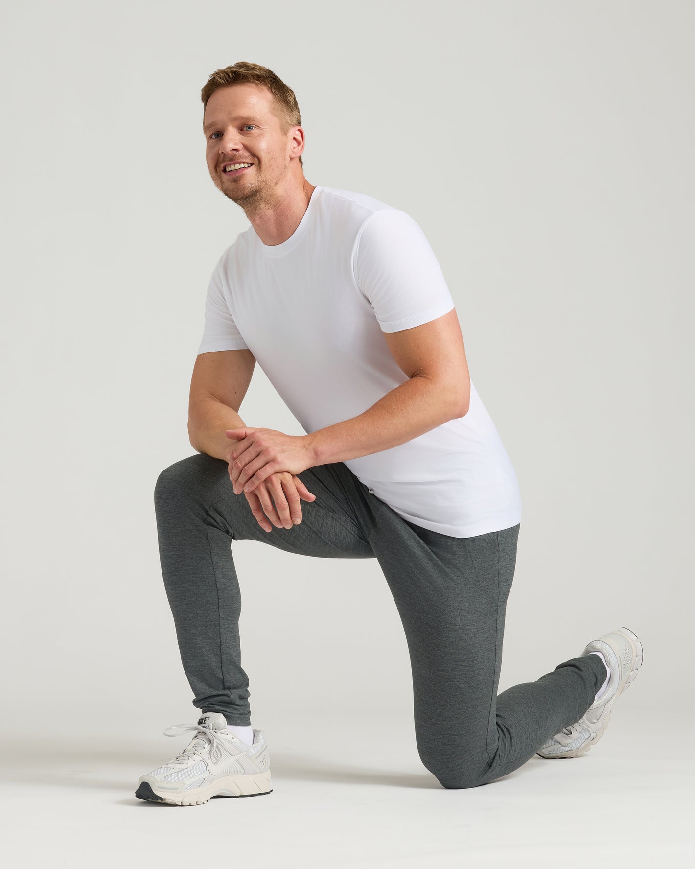 Man wearing Charcoal Heather Gray Tall Active Joggers, kneeling, showcasing slim fit.