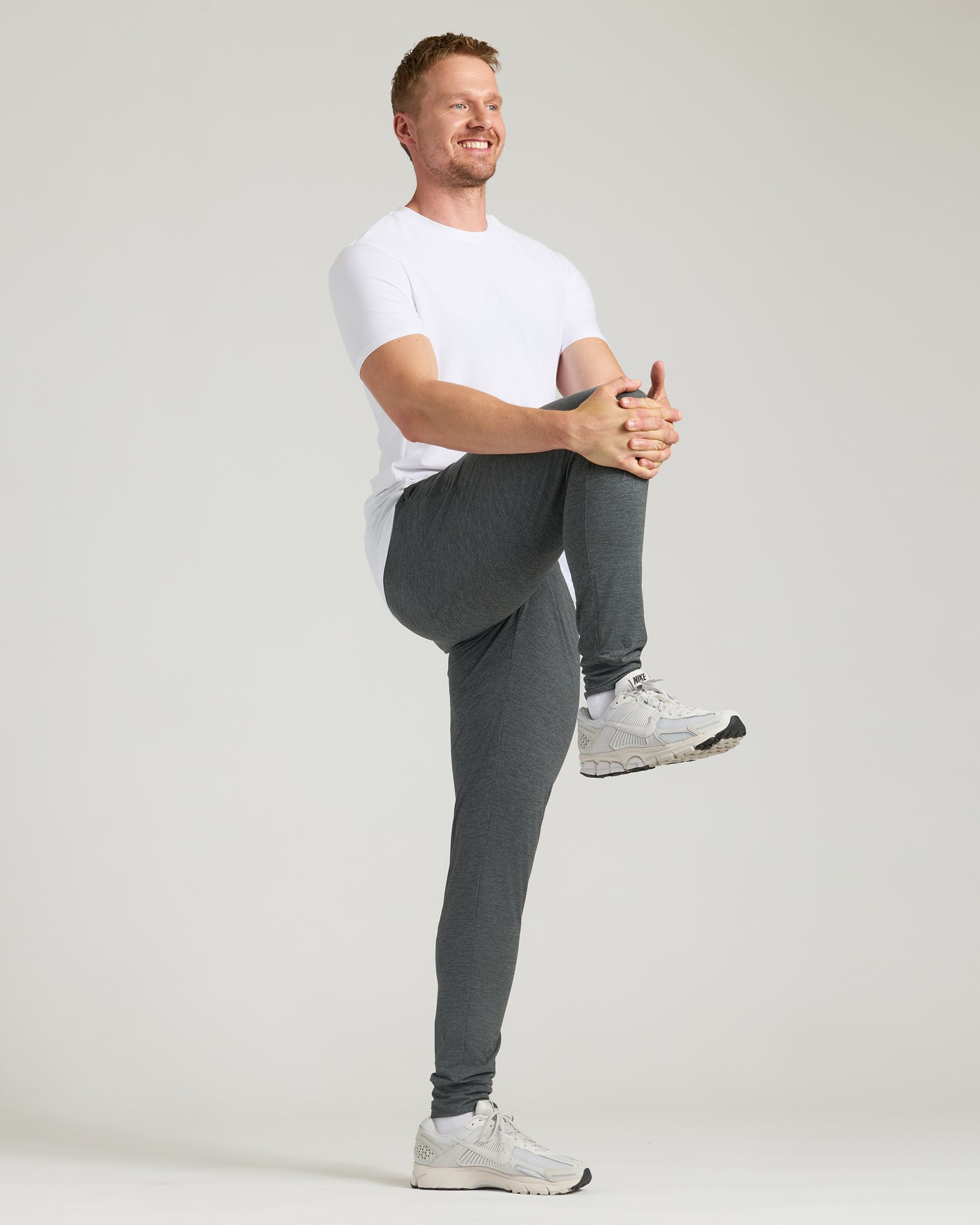 Man in Tall Active Joggers 3-Pack, stretching in athletic pants.