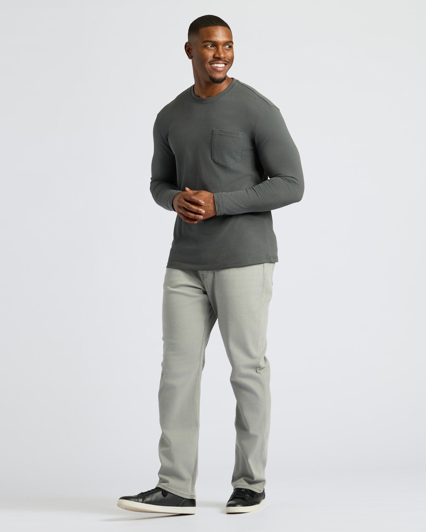 Young man wearing Carbon Tall Heavyweight Long Sleeve Pocket Crew, smiling confidently.